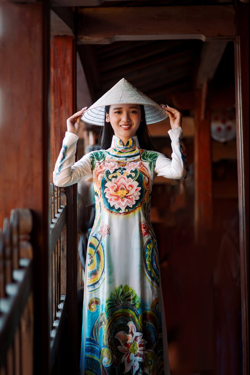 Home A young woman wearing a traditional Ao Dai and conical hat in Hội An, Vietnam.